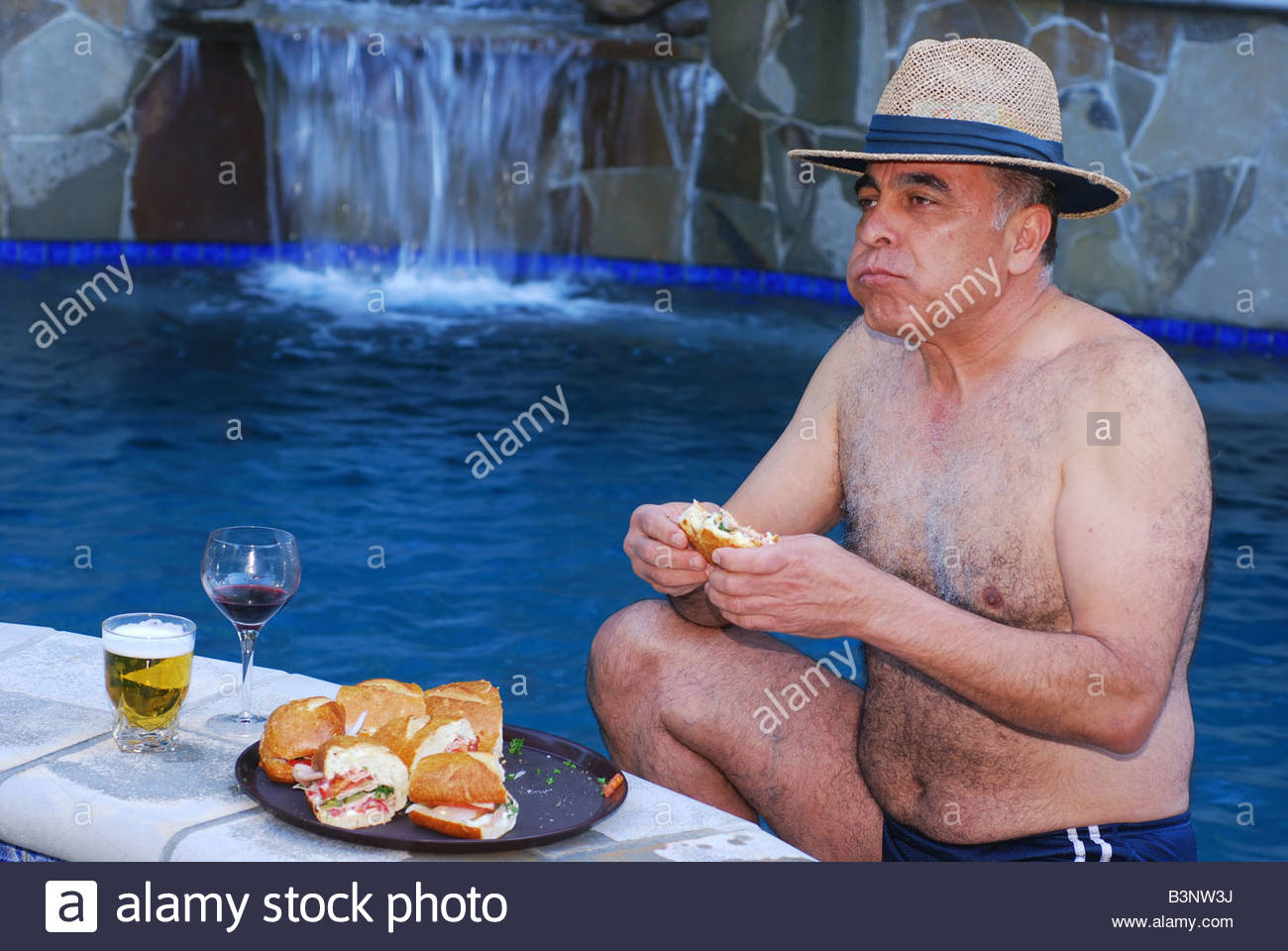 middle-eastern-man-enjoying-a-sub-sandwich-by-a-pool-at-a-resort-B3NW3J.jpg